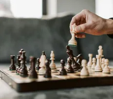 Hand zieht Schachfigur auf Schachbrett, visualisiert strategische Markenpositionierung